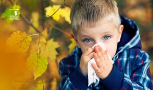 chłopiec na tle jesiennych liści wyciera nos